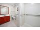Accessible bathroom featuring a red vanity, toilet, and a walk-in tiled shower with grab bars at 5065 Nesbit Ferry Ln, Atlanta, GA 30350