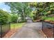 View of the home's exterior and long driveway, framed by a black metal fence at 5065 Nesbit Ferry Ln, Atlanta, GA 30350