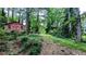 Backyard featuring mature trees, green grass, and a red storage shed at 5508 Zanola Sw Dr, Mableton, GA 30126