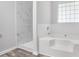 Elegant bathroom featuring a white tub with a tile surround, a separate walk-in shower, and a window at 5380 Bridle Point Pkwy, Snellville, GA 30039