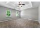 Spacious bedroom featuring plush carpet, neutral walls, and tray ceiling with fan at 1086 Erie Cir, Stone Mountain, GA 30087
