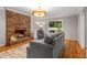 Comfortable living room with a brick fireplace, hardwood floors, a plush sofa, and a large window overlooking the outdoors at 2892 Guinevere Ne Dr, Atlanta, GA 30345