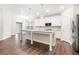 Open-concept kitchen with center island, white cabinets, stainless steel appliances, and hardwood floors at 3514 Ambassador Aly, Scottdale, GA 30079