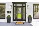 Inviting front porch featuring a sleek black door flanked by stylish light fixtures and potted plants at 560 Morgan Ne St, Atlanta, GA 30308
