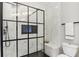 Bathroom featuring a modern shower with black grid door and marble tiling at 560 Morgan Ne St, Atlanta, GA 30308