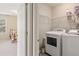 Well-lit laundry room with white washer and dryer and wire shelving, adjoining bedroom is visible at 105 Pine Valley Ct, Hiram, GA 30141