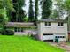 Split-level home with brick facade, lush greenery, attached garage with damaged door and overgrown yard at 3429 Pheasant Ct, Decatur, GA 30034
