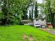 Split-level home with brick facade, lush greenery, attached garage, and overgrown yard at 3429 Pheasant Ct, Decatur, GA 30034
