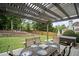 Backyard patio with dining set, hot tub and pergola against a backdrop of mature trees and lush landscaping at 4320 Cody Ct, Cumming, GA 30040