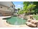 Backyard pool featuring a custom rock waterfall and mature landscaping for a luxurious outdoor experience at 103 Millstone Way, Canton, GA 30115