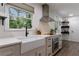 Bright kitchen featuring a farmhouse sink, stainless hood vent, and updated cabinets and appliances at 1600 Donna Sw St, Mableton, GA 30126