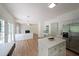 Bright, open kitchen with white cabinets, island, stainless steel refrigerator, and access to living room with fireplace at 405 Rosedown Way, Lawrenceville, GA 30043