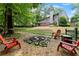 Secluded backyard with fire pit, red Adirondack chairs, a spacious lawn, and a lovely deck with pergola at 5885 Millstone Dr, Cumming, GA 30028