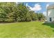 Large backyard with an expansive lawn, a line of trees, privacy fence, and a partially covered porch at 2479 Mitford Ct, Dacula, GA 30019