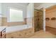 A tiled bathroom with a bathtub and shower with a glass door, and an entrance to the closet at 2479 Mitford Ct, Dacula, GA 30019
