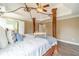 Spacious bedroom featuring a tray ceiling, ceiling fan, and a four-poster bed with a decorative frame at 2479 Mitford Ct, Dacula, GA 30019