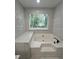 Bathroom featuring a soaking tub with white marble-look tile surround at 2720 Thornbury Way, Atlanta, GA 30349