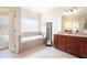 Well-lit bathroom with a soaking tub, tile flooring, and cherry wood vanity at 585 Lawton Bridge Sw Rd, Smyrna, GA 30082