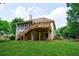 View of the home's back exterior with a deck and a screened-in porch, surrounded by grass and trees at 6455 Ivey Meadow Ln, Cumming, GA 30040
