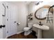 Stylish half bathroom featuring a pedestal sink, round mirror, and sleek fixtures, ideal for guests at 6455 Ivey Meadow Ln, Cumming, GA 30040