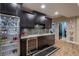 Finished basement bar with granite counters, dark wood cabinets, wine cooler, beverage fridge, and tile backsplash at 1984 Mendenhall Cir, Atlanta, GA 30341