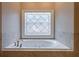 Close-up of a soaking tub featuring tile surround and a decorative window at 1984 Mendenhall Cir, Atlanta, GA 30341