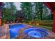 Inviting backyard pool and spa illuminated at dusk surrounded by lush trees at 1984 Mendenhall Cir, Atlanta, GA 30341