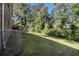 Grassy backyard with mature trees and landscaping surrounded by a chain link fence at 863 Needle Rock Dr, Stonecrest, GA 30083