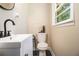 Bathroom featuring a black faucet, white sink, and toilet with a window at 863 Needle Rock Dr, Stonecrest, GA 30083