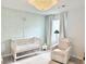 Charming Bedroom with stylish wallpaper, crib, comfortable armchair, and decorative ceiling light at 306 Coppergate Ct, Holly Springs, GA 30115