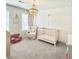 Cozy Bedroom features a wooden crib, comfortable armchair, neutral decor, and soft lighting at 306 Coppergate Ct, Holly Springs, GA 30115