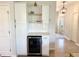 Stylish butler's pantry offers a beverage fridge, floating shelves, white subway tile backsplash, and white cabinetry at 306 Coppergate Ct, Holly Springs, GA 30115