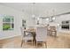 Dining area with a modern chandelier, wood-look floors, access to the kitchen, and views of the outdoors at 306 Coppergate Ct, Holly Springs, GA 30115