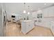 Bright kitchen with white cabinets, a center island, and an open view into the living room and dining area at 306 Coppergate Ct, Holly Springs, GA 30115