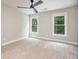 A neutrally decorated bedroom with two windows, carpeted floor, a ceiling fan, and a white door at 5635 Upper Creek Ct, Suwanee, GA 30024