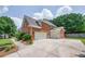 Side view showing an extra wide concrete driveway, 3-car garage, lawn, and lush trees behind at 5635 Upper Creek Ct, Suwanee, GA 30024
