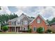 Beautiful two-story home featuring brick and stone facade with a manicured front lawn and mature trees at 5635 Upper Creek Ct, Suwanee, GA 30024