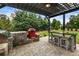 Outdoor kitchen featuring built-in grill, bar seating and lush green surroundings at 4010 Cameron Ct, Cumming, GA 30040