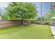 Lush backyard with artificial turf, a mature shade tree, bench seating, and privacy fence at 470 Wagon Hill Ln, Sugar Hill, GA 30518