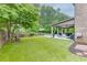 Grassy backyard featuring an in-ground pool, covered patio, and lush landscaping, perfect for relaxing or entertaining at 470 Wagon Hill Ln, Sugar Hill, GA 30518