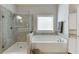 Bright bathroom featuring tiled shower and soaking tub with a large window at 470 Wagon Hill Ln, Sugar Hill, GA 30518