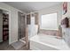 Bathroom featuring a shower, soaking tub, tiled flooring and a frosted window at 397 Victory Ln Ln, Locust Grove, GA 30248