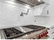 Close-up of a stainless steel range with red knobs and white herringbone backsplash at 4927 Slaton Dr, Acworth, GA 30101