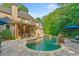Gorgeous backyard pool with a stone waterfall, covered patio, and lush landscaping for ultimate relaxation at 4304 Berkford Ne Cir, Brookhaven, GA 30319