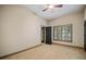Neutral carpeted bedroom featuring a ceiling fan, window with shutters, and a view to the outside at 4304 Berkford Ne Cir, Brookhaven, GA 30319