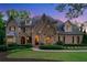 Charming brick home with manicured landscaping, arched entryway, and inviting exterior lighting at twilight at 4304 Berkford Ne Cir, Brookhaven, GA 30319