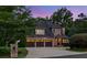 Brick home with a three-car garage and beautiful landscaping and stone mailbox post at twilight at 4304 Berkford Ne Cir, Brookhaven, GA 30319