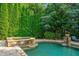Spa and pool featuring stone accents and lush greenery that provides privacy and enhances the outdoor ambiance at 4304 Berkford Ne Cir, Brookhaven, GA 30319