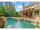 Resort-style pool with waterfall features surrounded by a lush green landscape and a covered patio area at 4304 Berkford Ne Cir, Brookhaven, GA 30319