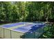 A view of community blue and green outdoor tennis courts surrounded by a dark fence and lush trees at 4304 Berkford Ne Cir, Brookhaven, GA 30319
